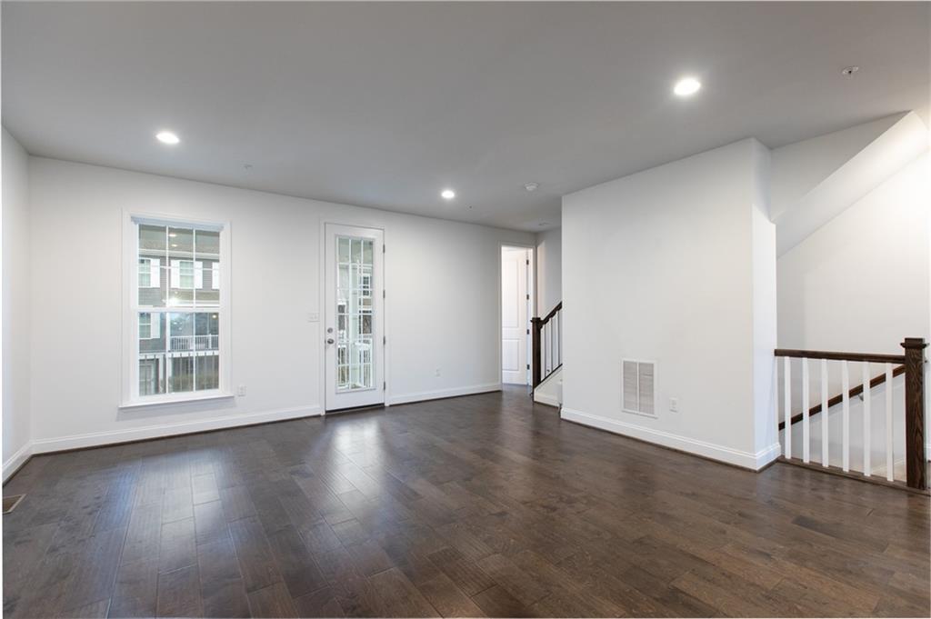 107 Gress Road Cranberry Township, PA 16066 - Photo 7 of 23 Recessed lighting provides a warm, even glow throughout the space, while large windows invite in natural light. A standout feature is the glass door leading to the covered porch, seamlessly extending the living area outdoors and creating the perfect setting for relaxing or entertaining.