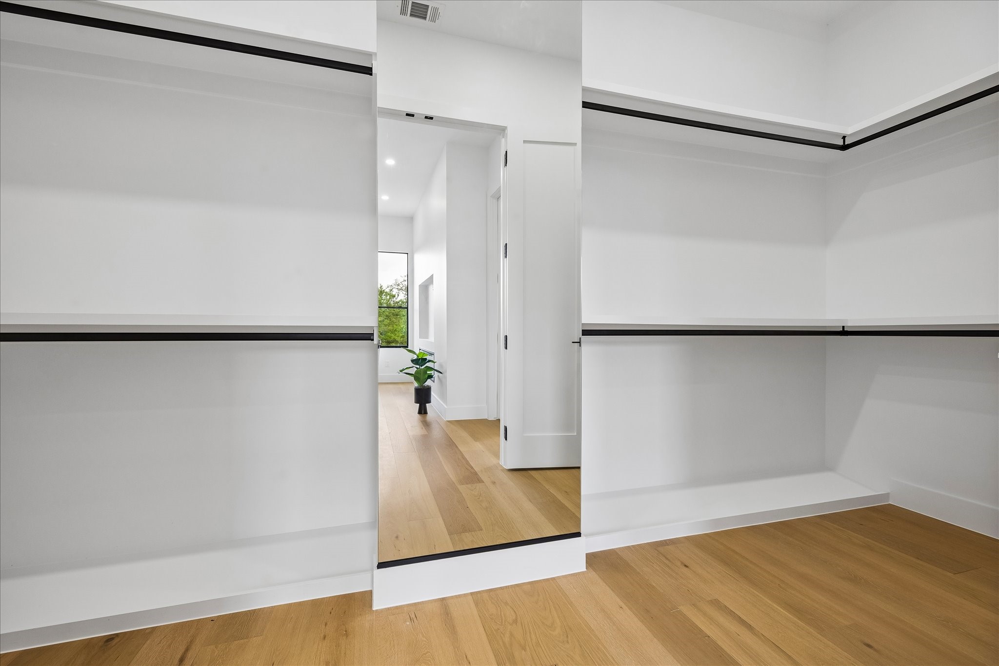 5430 Rutherglenn Drive Houston, TX 77096 - Photo 17 of 31 Spacious walk-in closet with sleek white shelves and a full-length mirror. The hardwood floors add warmth, and there’s plenty of space for all your needs.