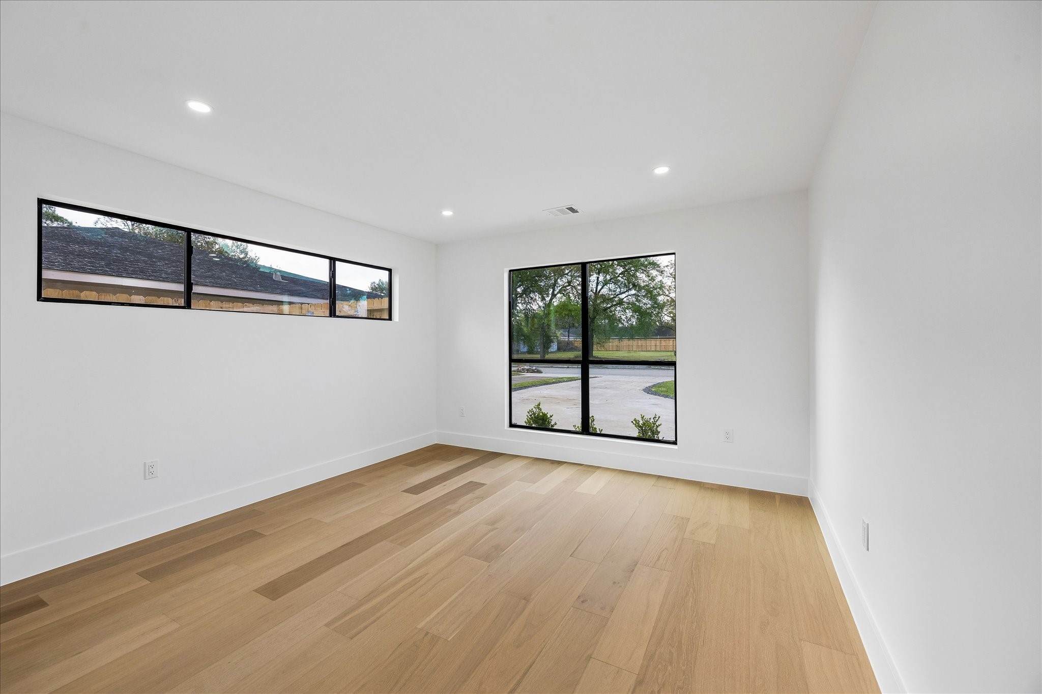 5430 Rutherglenn Drive Houston, TX 77096 - Photo 19 of 31 This room features a modern, minimalistic design with light wood flooring and white walls. It has large windows providing ample natural light and views of the outdoors, creating a bright and inviting space.