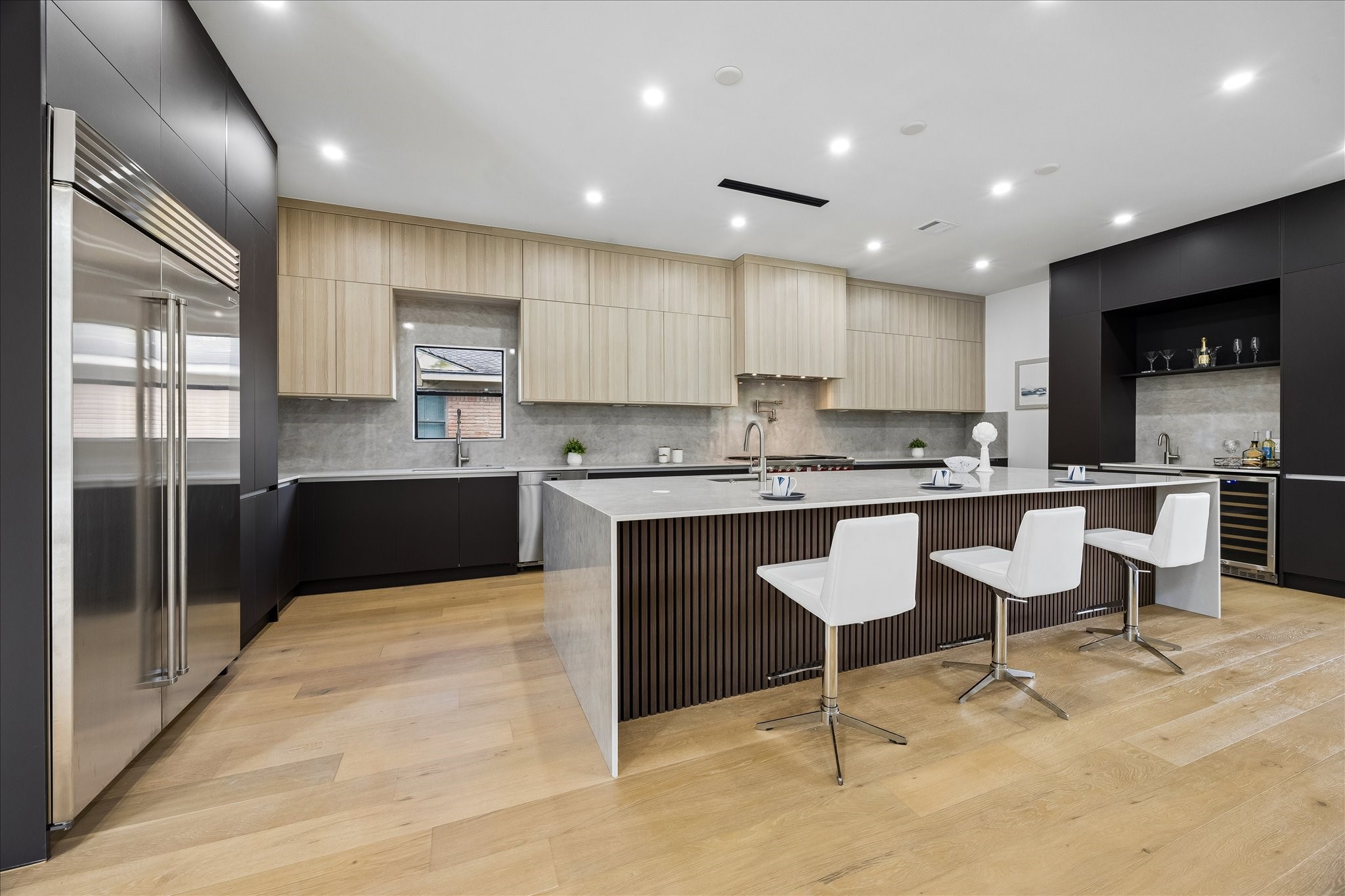 5430 Rutherglenn Drive Houston, TX 77096 - Photo 2 of 31 Wow!!! Modern kitchen with sleek cabinetry, a large island with seating, and high-end stainless steel appliances. The space features ample lighting, hardwood floors, and a minimalist design for a clean, contemporary look.