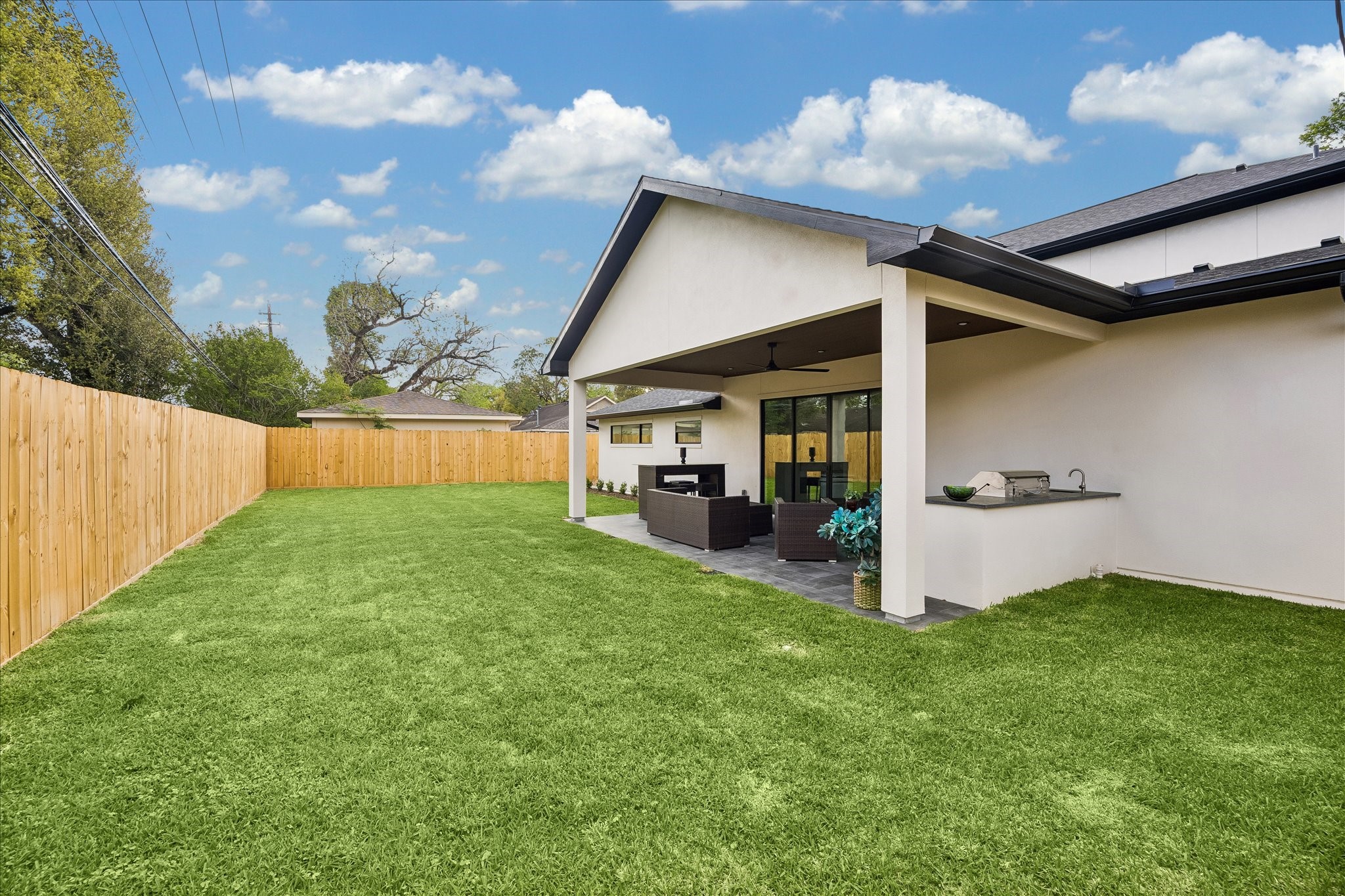 5430 Rutherglenn Drive Houston, TX 77096 - Photo 25 of 31 Very spacious backyard with a well-maintained lawn and a modern covered patio equipped with outdoor seating and a built-in grill and outdoor kitchen- perfect for entertaining and special gatherings.