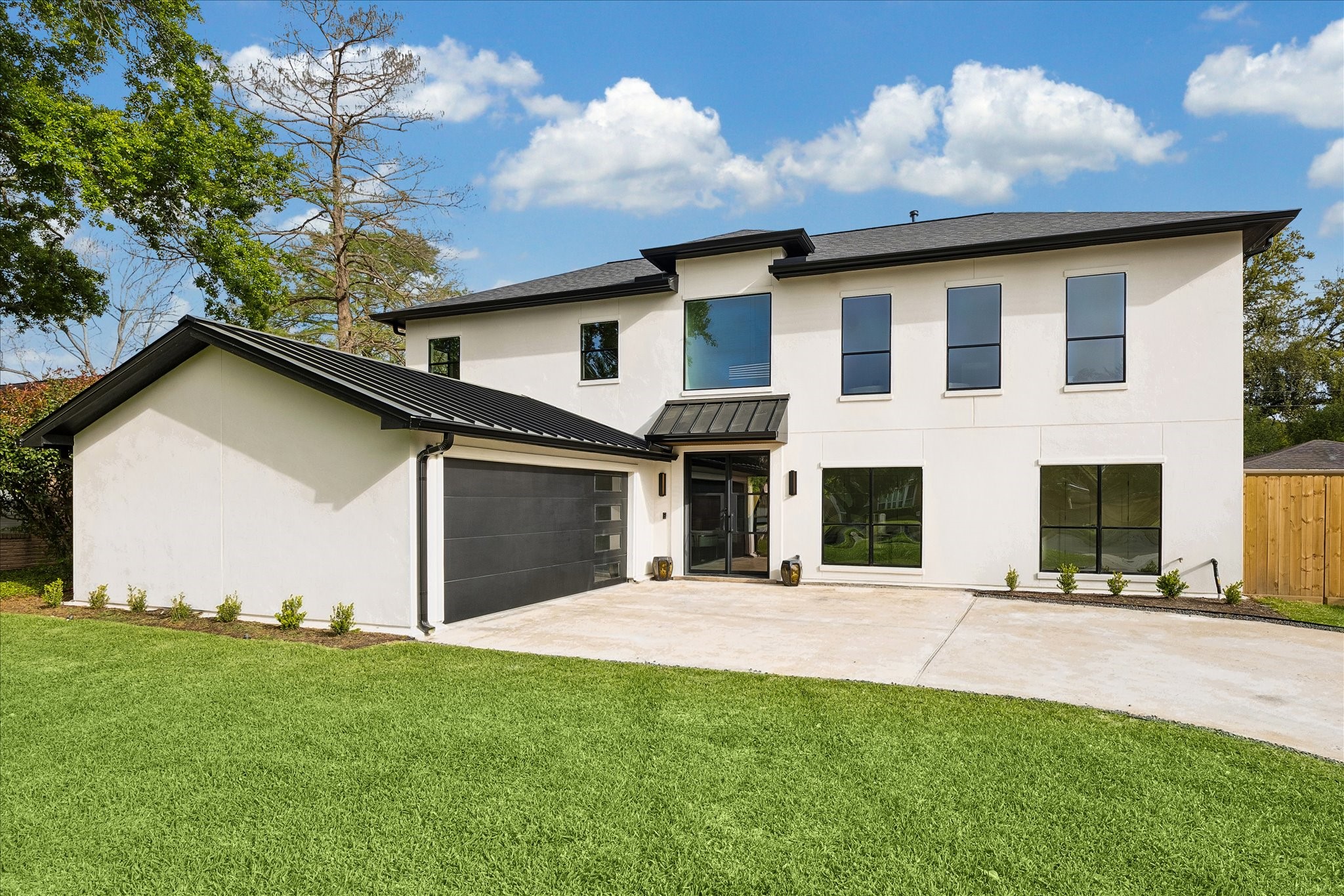 5430 Rutherglenn Drive Houston, TX 77096 - Photo 28 of 31 This modern two-story home features a sleek black and white exterior with large windows and a spacious driveway leading to a two-car garage. The well-maintained lawn and simple landscaping enhance its contemporary appeal.