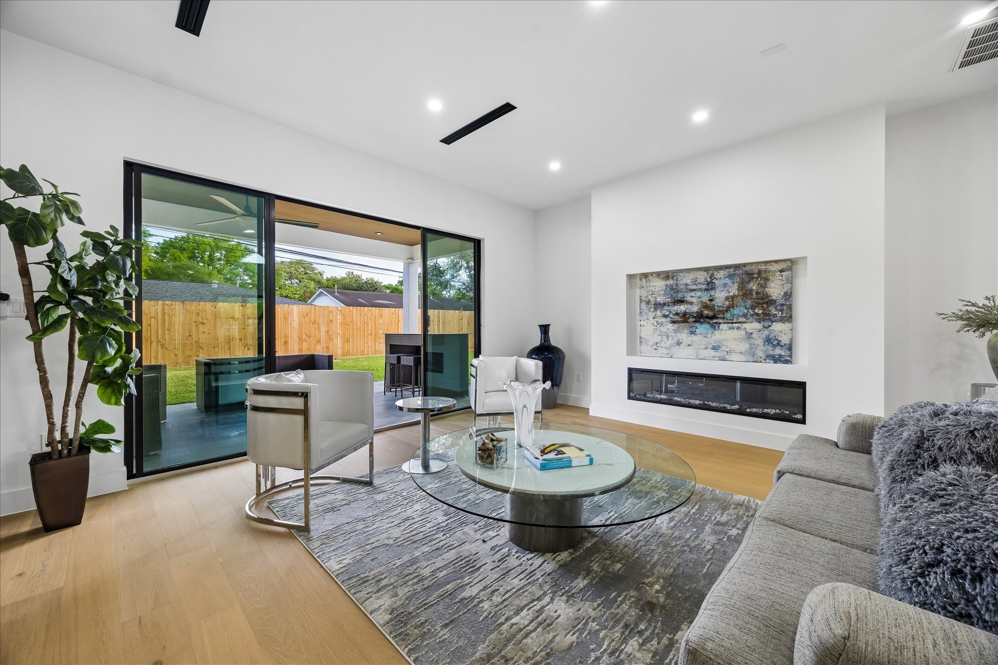 5430 Rutherglenn Drive Houston, TX 77096 - Photo 5 of 31 Open layout with sleek hardwood floors and a large sliding glass door leading to a outdoor kitchen and covered patio. It includes a contemporary fireplace and ample natural light, creating a bright and inviting space.