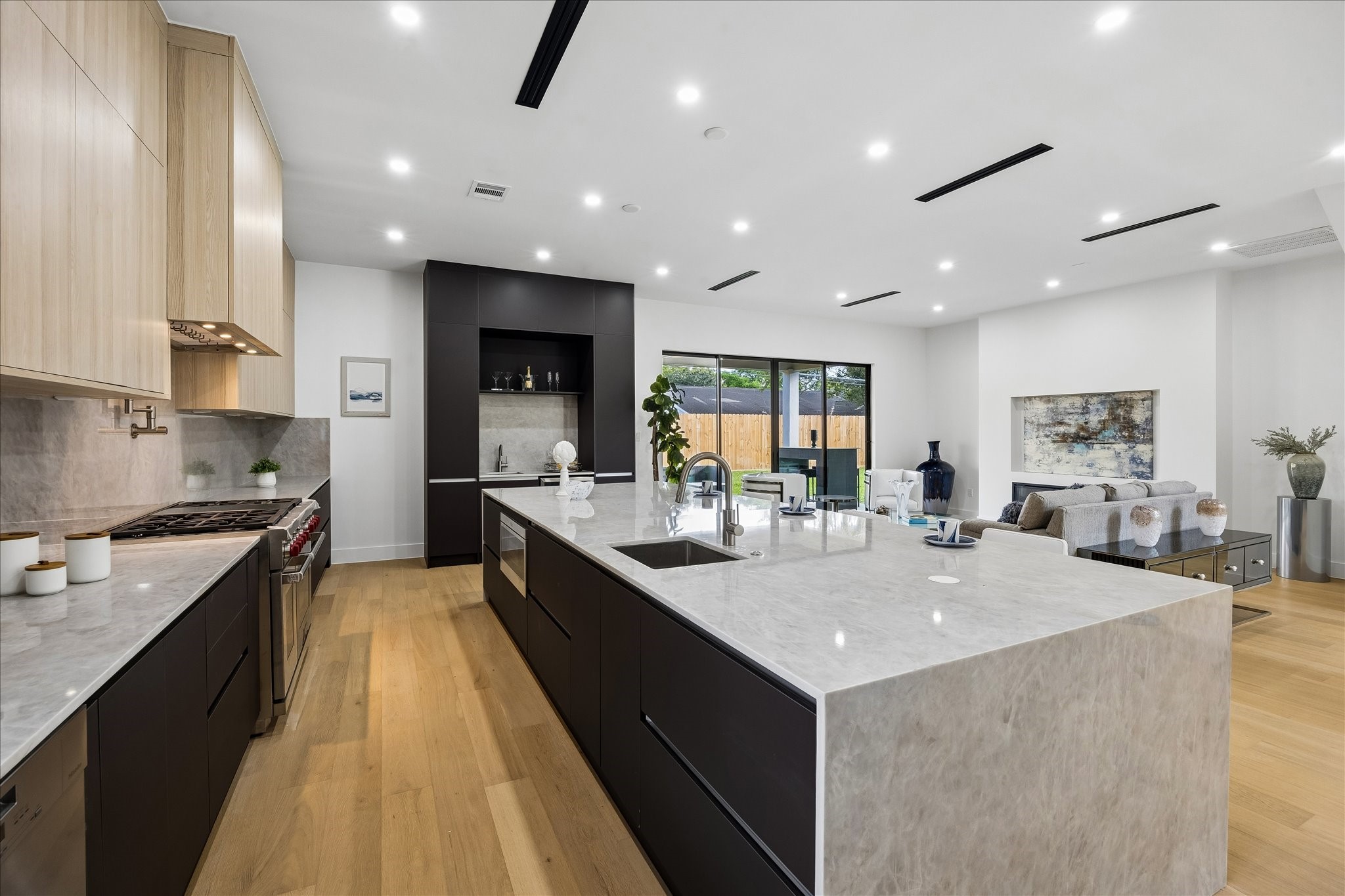 5430 Rutherglenn Drive Houston, TX 77096 - Photo 8 of 31 The gourmet kitchen with upgraded Wolf stainless steel appliances features sleek cabinetry, a large island with marble countertops, and ample natural light from expansive windows. The space is complemented by hardwood floors and recessed lighting, offering a stylish and functional setting for entertaining.