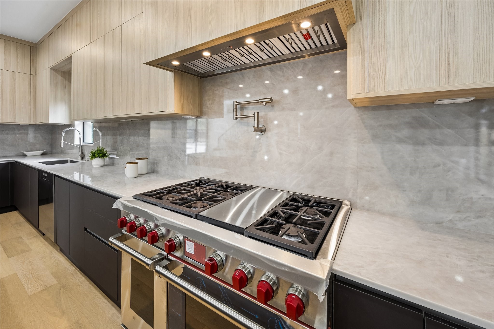 5430 Rutherglenn Drive Houston, TX 77096 - Photo 9 of 31 Modern kitchen with sleek cabinetry, a high-end Wolf gas stove, and a stylish backsplash. Features a pot filler and ample counter space for a gourmet cooking experience.