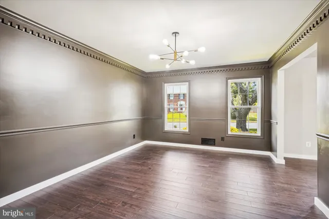 an empty room with wooden floor mirror and windows