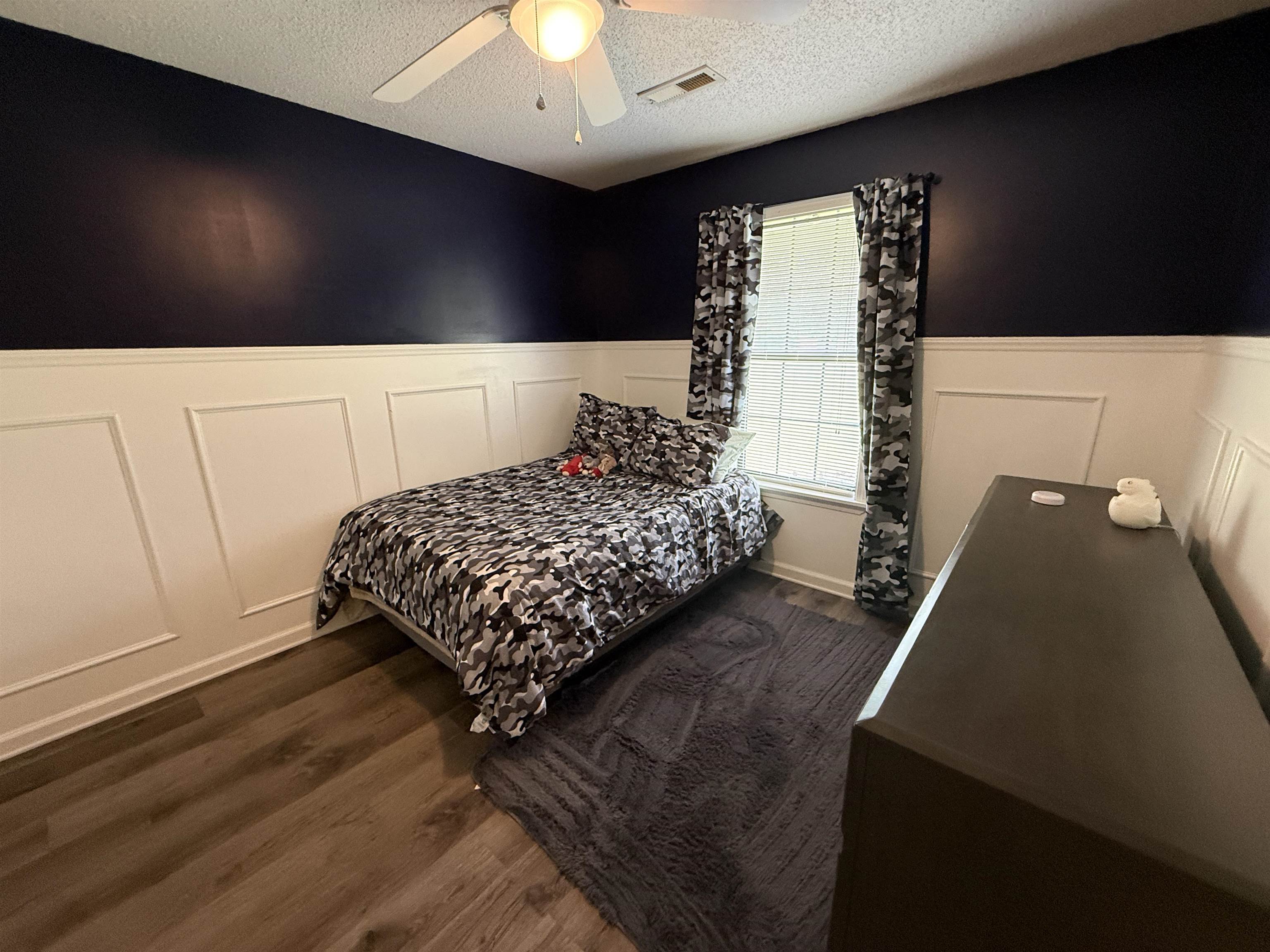 185 Mignon Road Atoka, TN 38004 - Photo 25 of 34 Room featuring wood-finish flooring, a window with blinds, a ceiling fan with light fixture, and wainscoting paneling