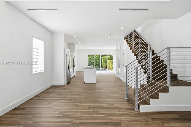 a view of an empty room with wooden floor and windows