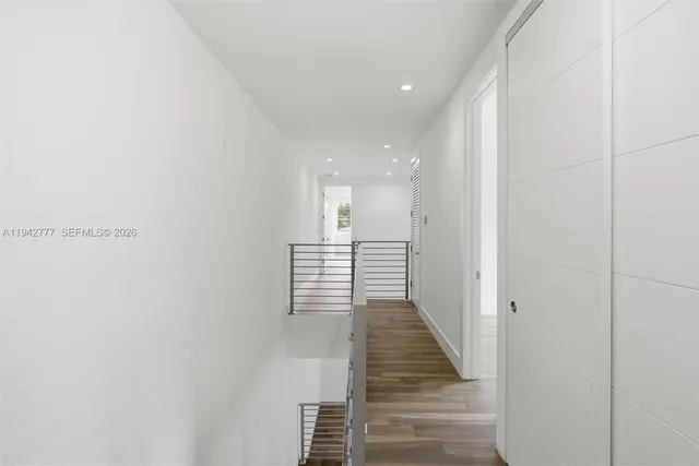 a view of a hallway with wooden floor and staircase