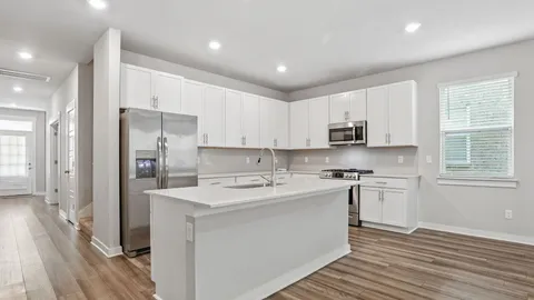 a kitchen with stainless steel appliances granite countertop a refrigerator a sink dishwasher a stove and white countertops with wooden floor