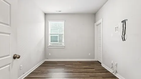 a view of an empty room with wooden floor and a window