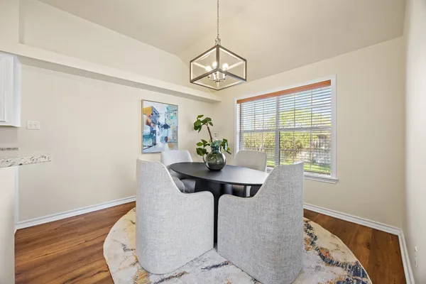 a dining room with chandelier and wooden floor