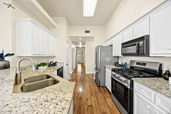 a kitchen with stainless steel appliances granite countertop a sink dishwasher stove and refrigerator with wooden floor
