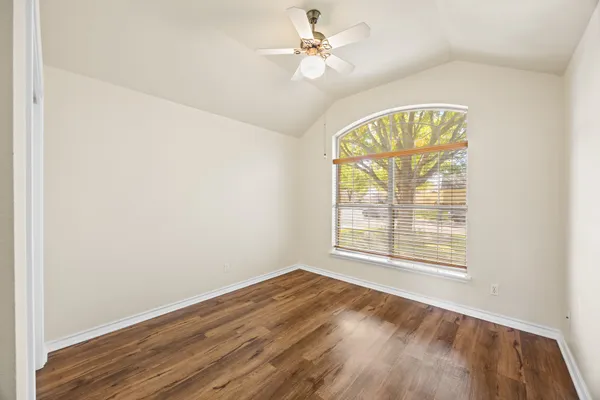 an empty room with windows and a chandelier fan