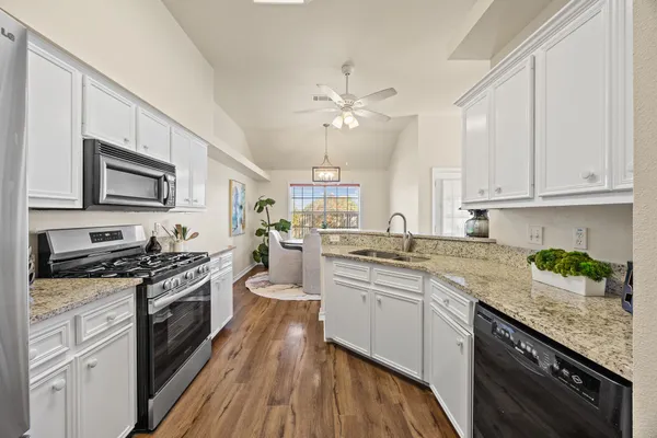a kitchen with granite countertop a sink a counter space appliances and cabinets