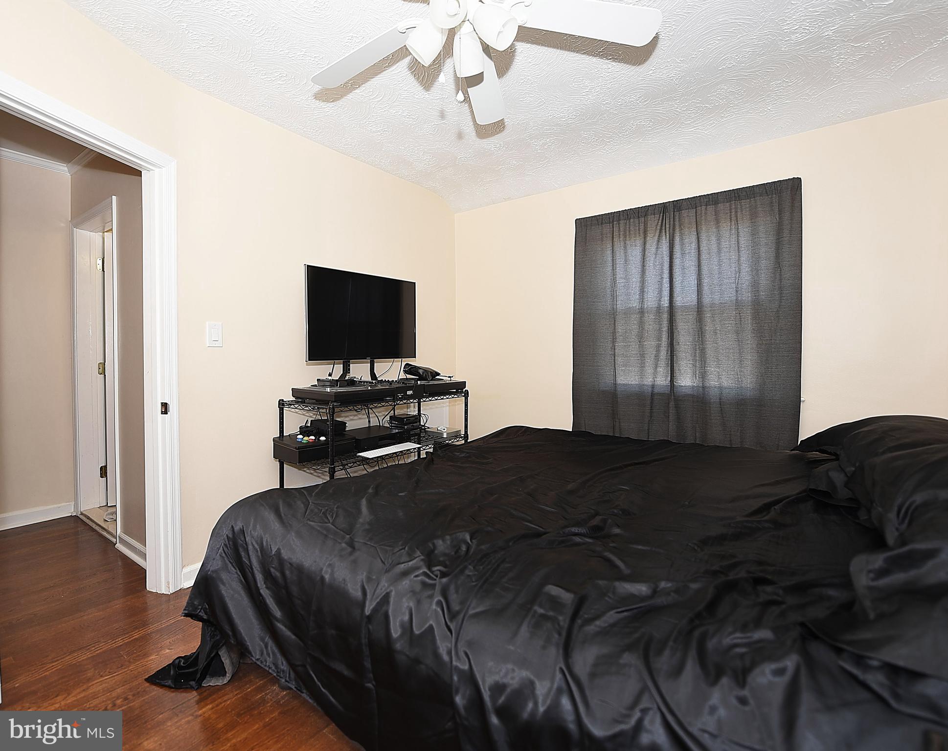 4423 Fenor Road Baltimore, MD 21227 - Photo 14 of 28 a bedroom with a bed tv and wooden floor