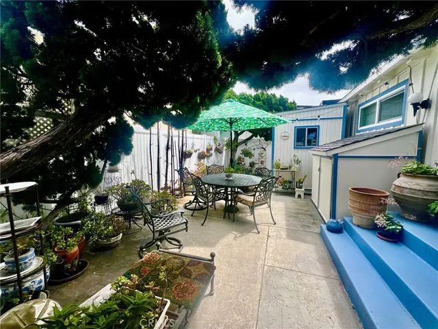 a view of a patio with table and chairs potted plants and large tree
