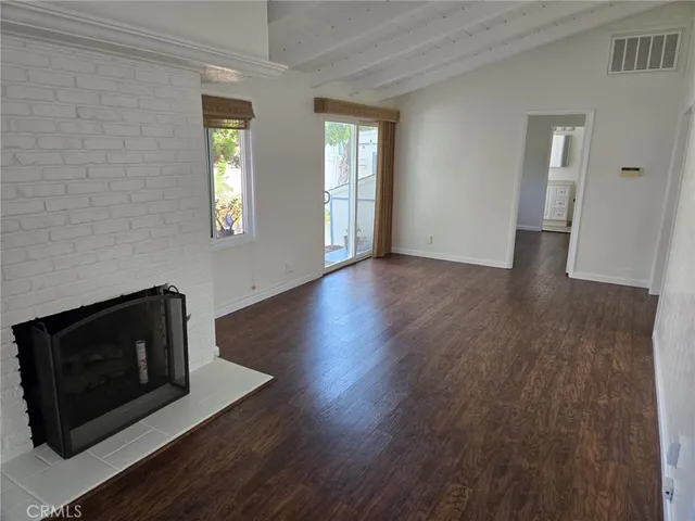 a view of an empty room with wooden floor and a fireplace