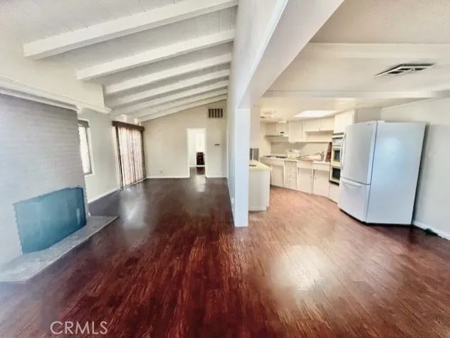 a view of a big room with wooden floor and a kitchen