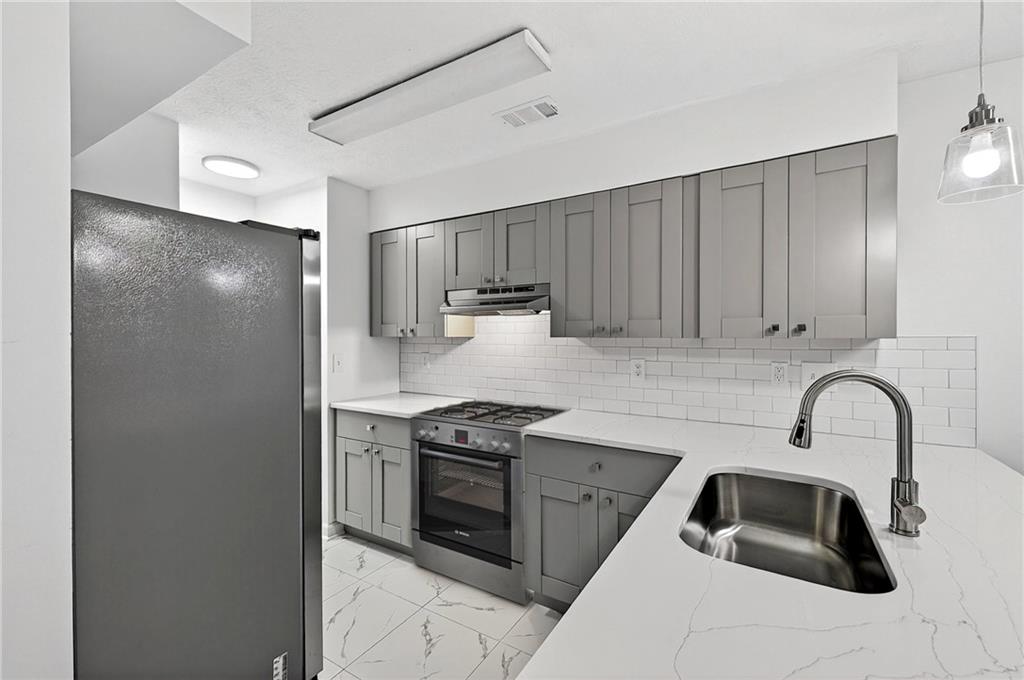 6716 Colchester Place Northwest Norcross, GA 30093 - Photo 6 of 23 a kitchen with stainless steel appliances a sink stove and cabinets