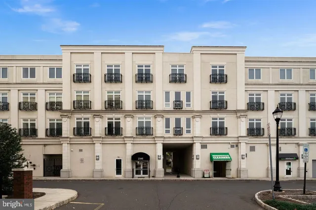 a front view of a building with glass windows and plants