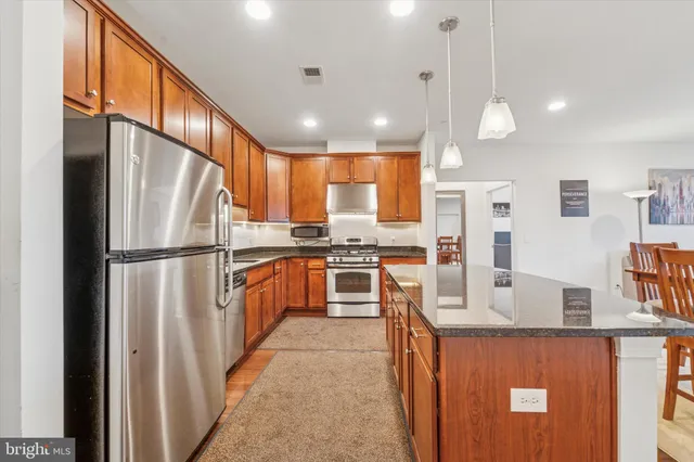 a kitchen with stainless steel appliances granite countertop a refrigerator a oven a sink dishwasher and white cabinets with wooden floor