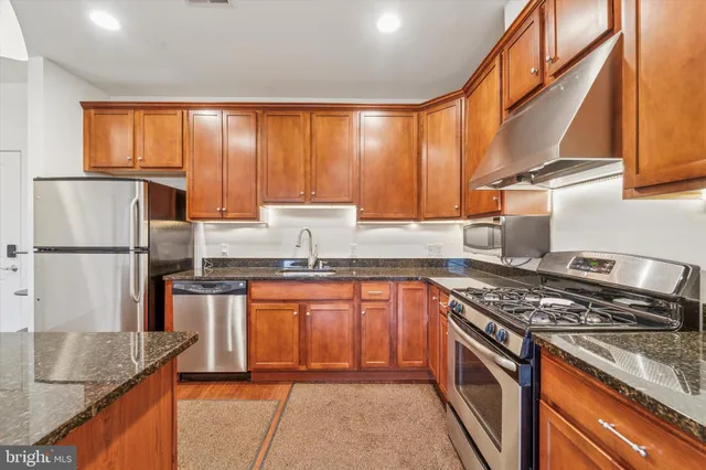 a kitchen with stainless steel appliances granite countertop a sink stove and refrigerator