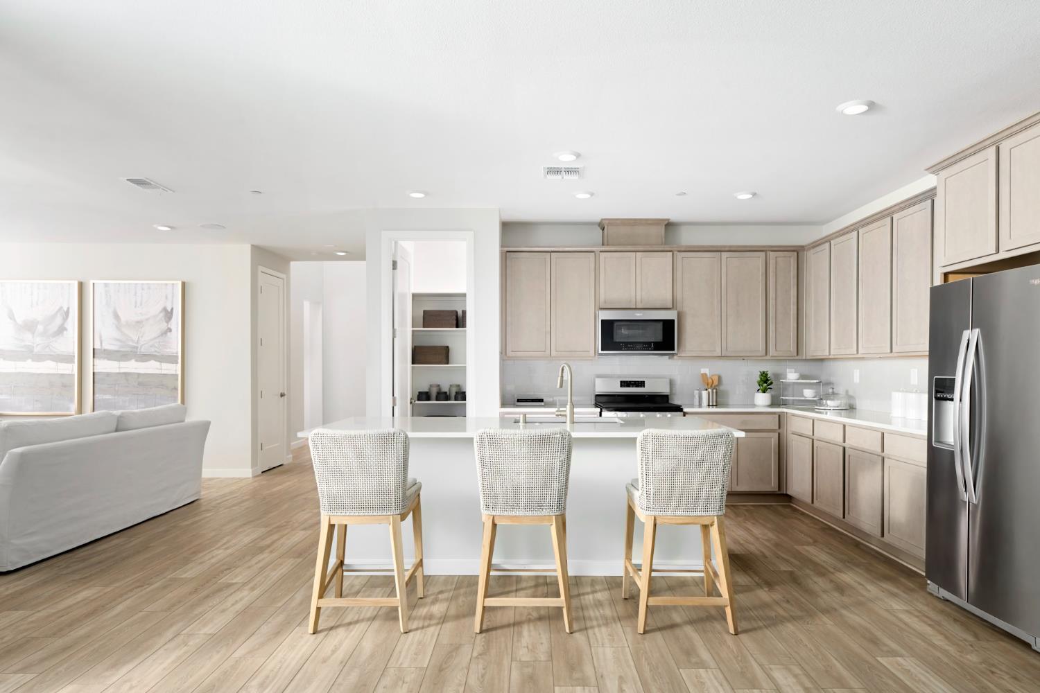 a kitchen with stainless steel appliances a dining table chairs microwave and refrigerator