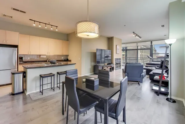 a kitchen with stainless steel appliances granite countertop a stove top oven a sink a dining table and chairs