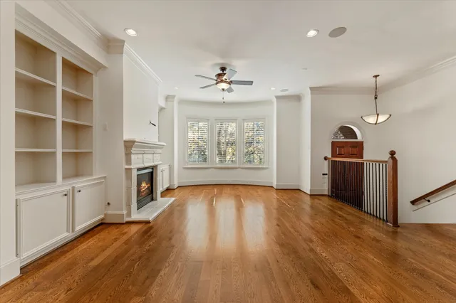 wooden floor in an empty room with a fireplace and a window