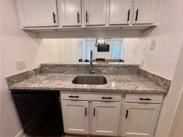 a kitchen with granite countertop a sink and cabinets