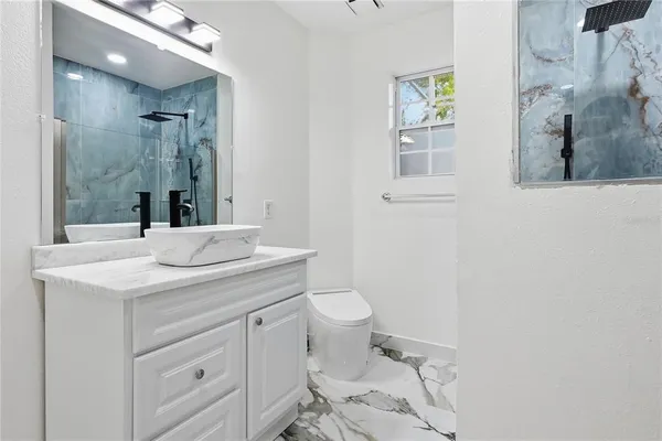 a bathroom with a granite countertop sink mirror vanity and toilet