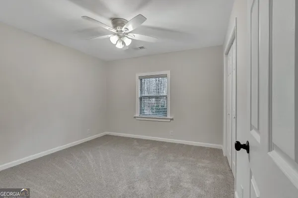 an empty room with furniture and a ceiling fan