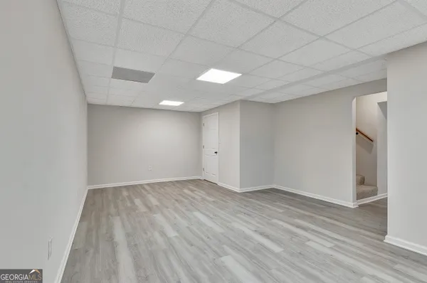 an empty room with wooden floor chandelier fan and windows