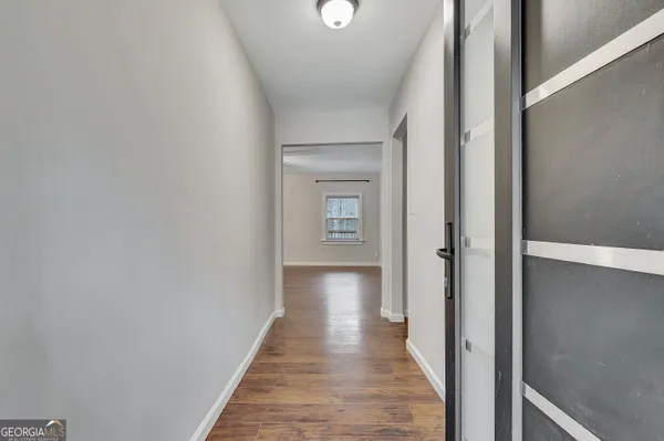 a view of an empty room with wooden floor and a window