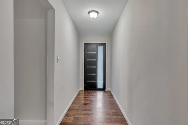 a view of empty room with wooden floor and kitchen view