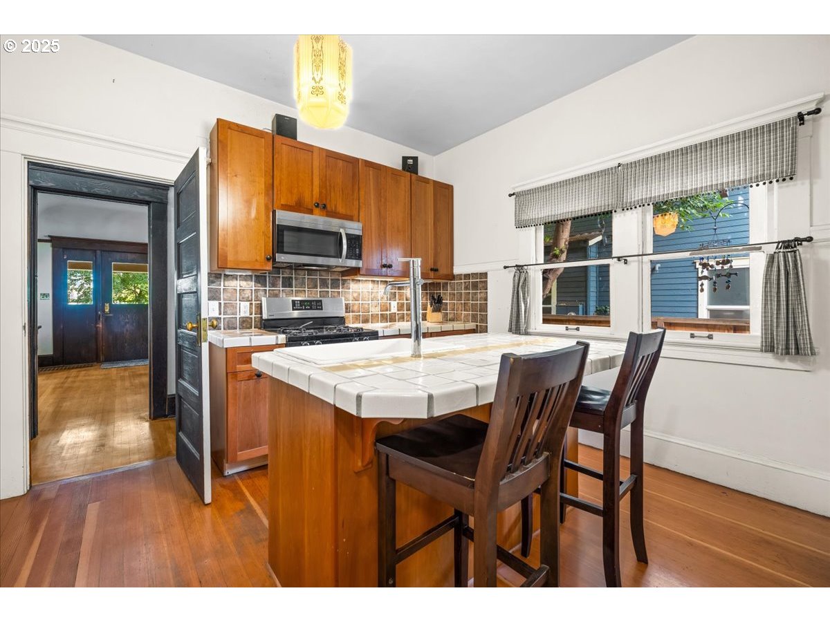 1844 Southeast 12th Avenue Portland, OR 97214 - Photo 14 of 48 a kitchen with stainless steel appliances kitchen island granite countertop a table chairs in it and a view of living room