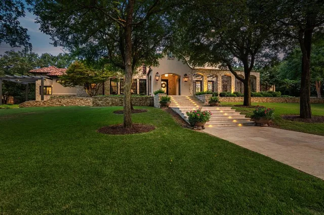 a front view of a house with a yard garden and trees
