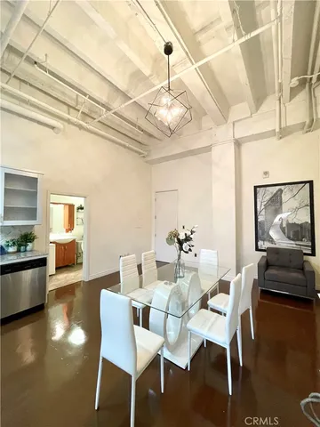a dining room with wooden floor a chandelier a glass table and chairs