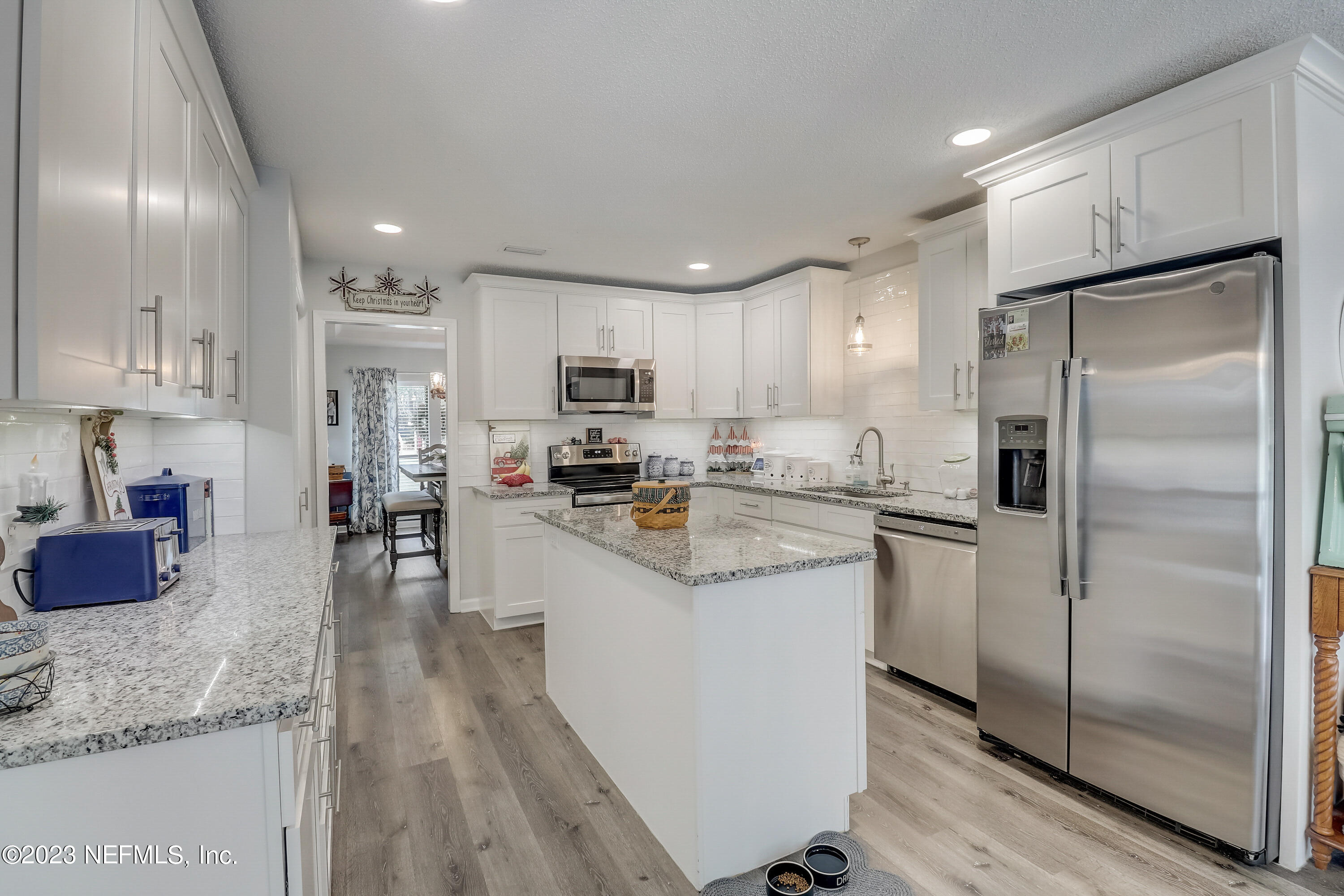 55377 Deer Run Road Callahan, FL 32011 - Photo 12 of 47 a kitchen with kitchen island granite countertop stainless steel appliances refrigerator sink and microwave