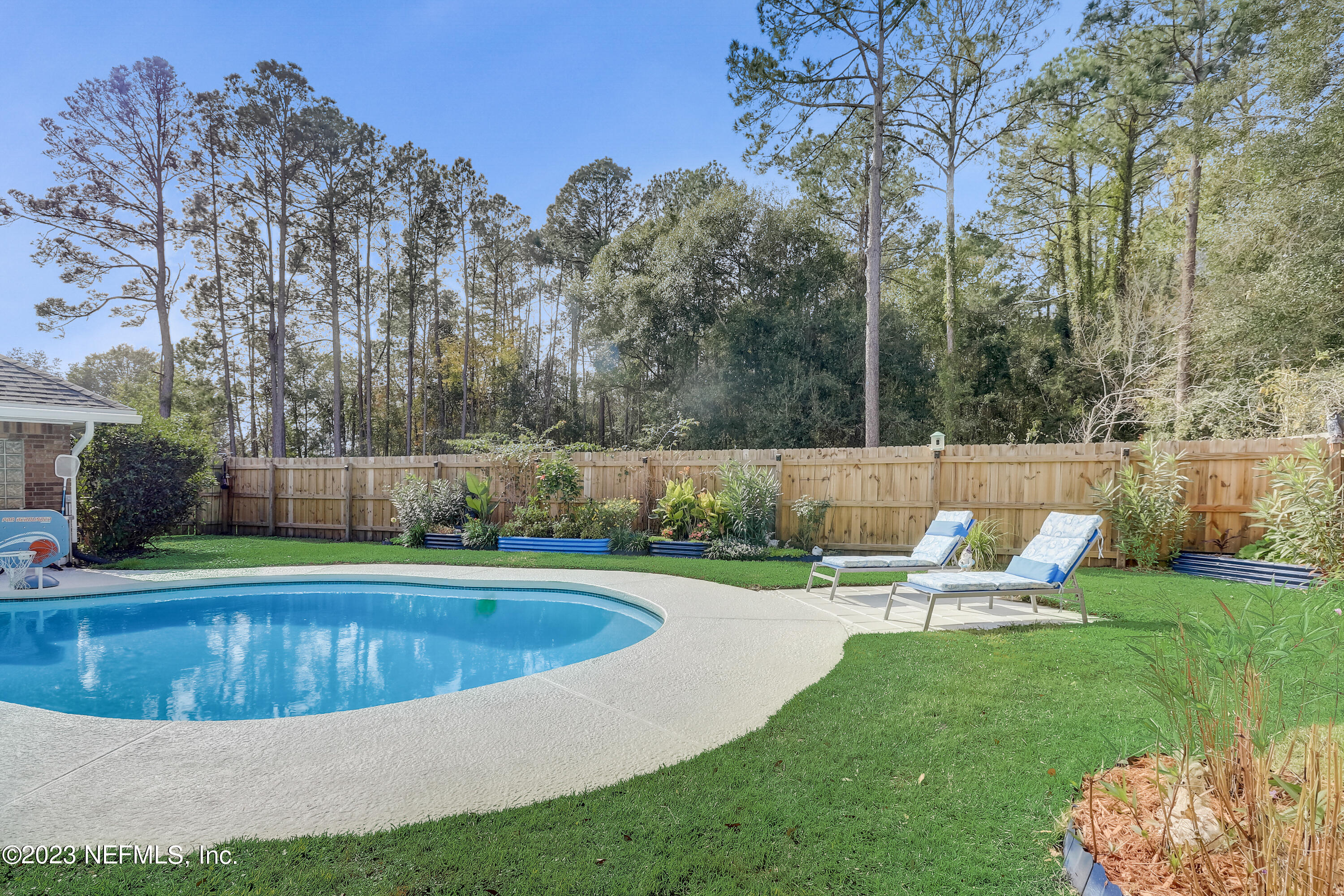 55377 Deer Run Road Callahan, FL 32011 - Photo 33 of 47 a view of a swimming pool with sitting area and trees in the background