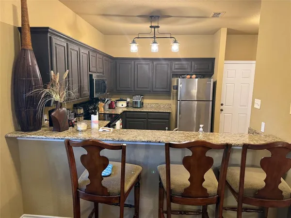 a kitchen with stainless steel appliances kitchen island granite countertop a table chairs and a refrigerator