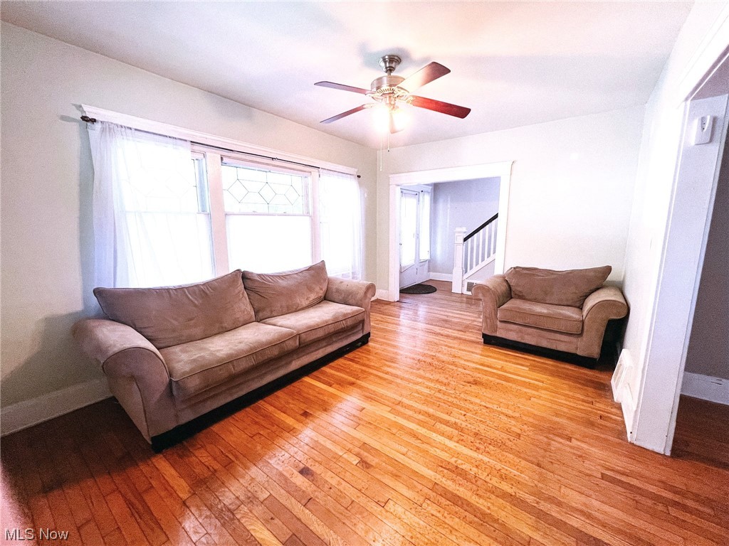 Hardwood floored living room featuring ceiling fan
