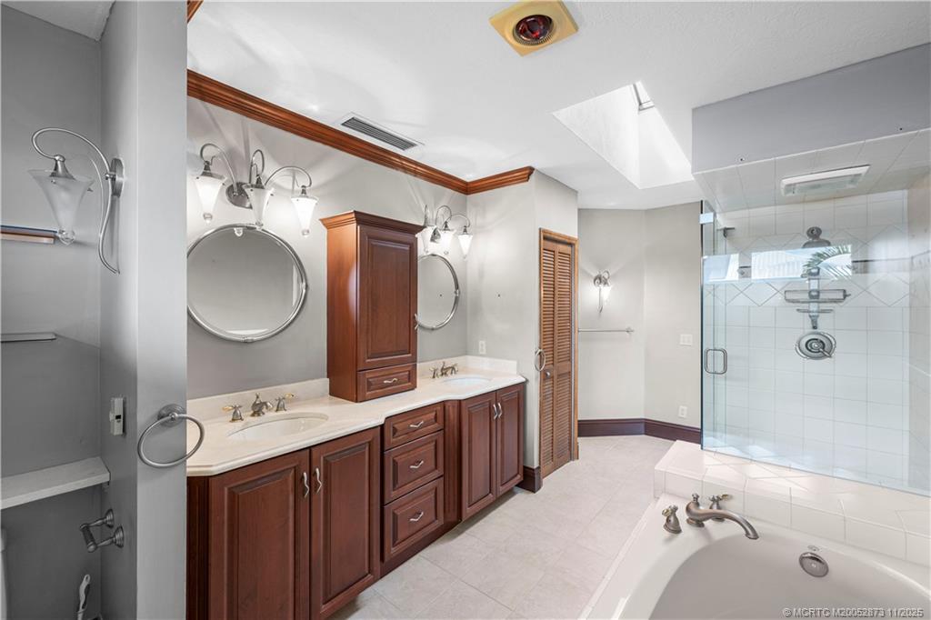 969 Southeast St Lucie Boulevard Stuart, FL 34996 - Photo 27 of 49 a bathroom with a tub sink double vanity and mirror