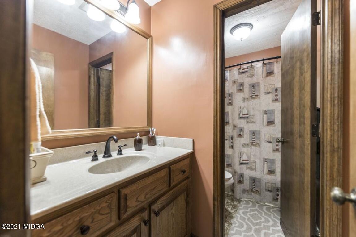 1471 Woolfolk Road Fort Valley, GA 31030 - Photo 30 of 51 a bathroom with a granite countertop sink a mirror and a shower