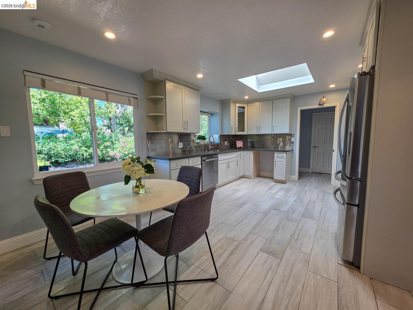 965 Springer Road Los Altos, CA 94024 - Photo 17 of 31 Contemporary kitchen featuring light wood-finish flooring, white cabinetry, dark countertops, and a full tile backsplash