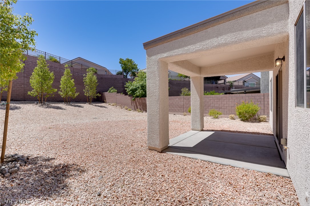 2717 Rimbaud Street Henderson, NV 89044 - Photo 14 of 34 An inviting covered patio opens onto a gravel yard with tiered landscaping, offering a private outdoor retreat.