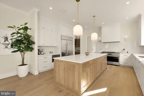 a kitchen with white cabinets and clock