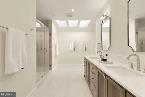 a bathroom with a double vanity sink a large mirror and a bathtub