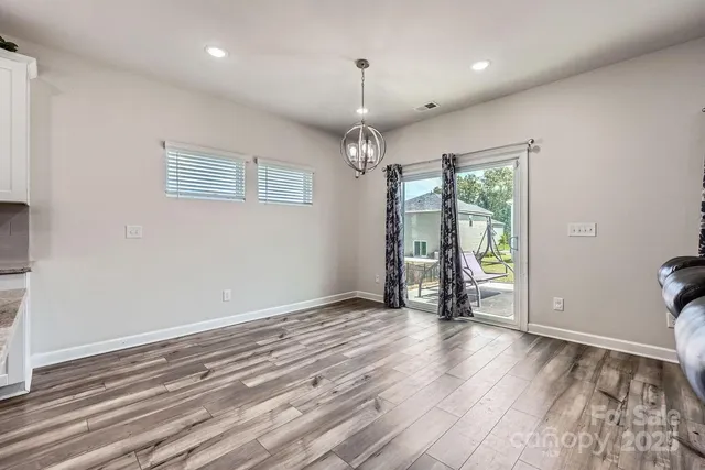 a view of a room with wooden floor fridge and a ceiling fan